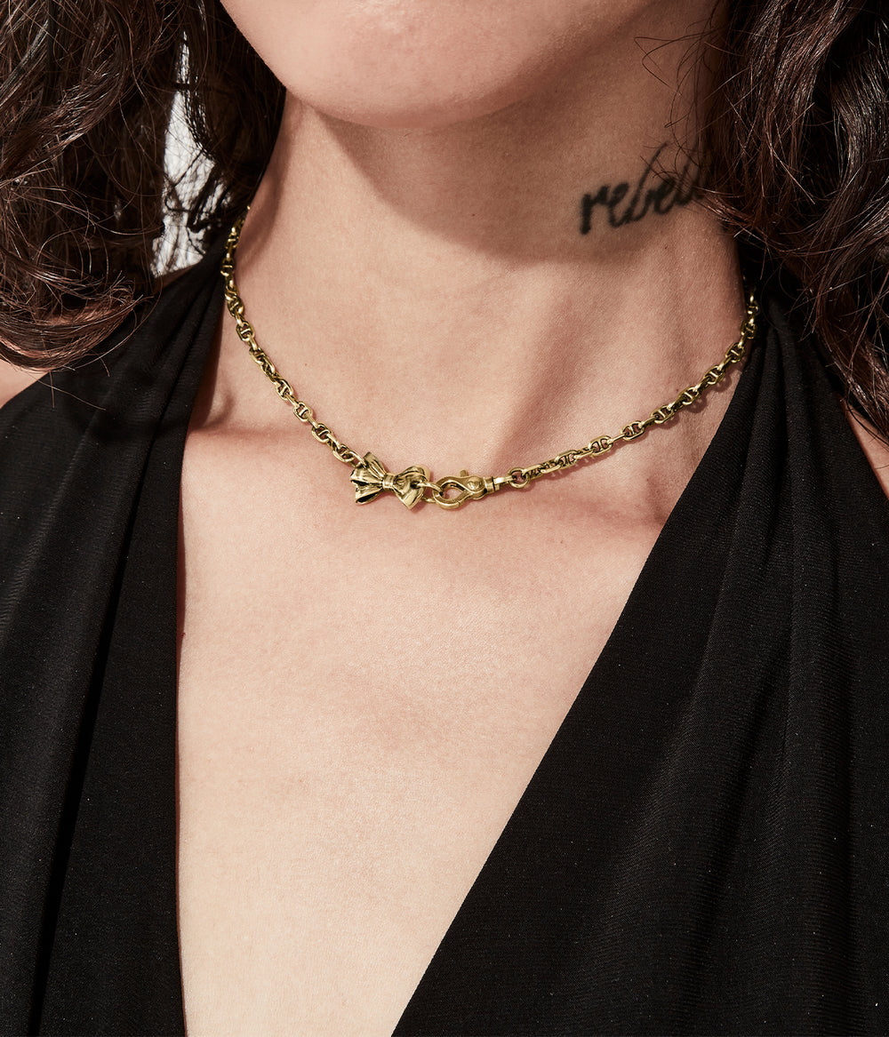 Necklace worn at collarbone to show gold tone and sculpted charm.