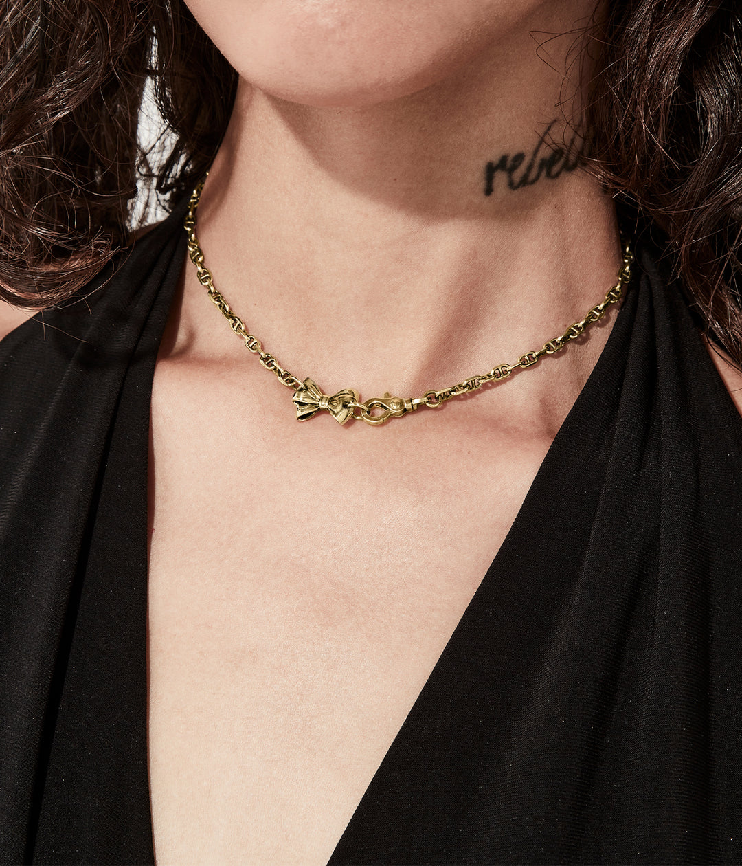 Necklace worn at collarbone to show gold tone and sculpted charm.
