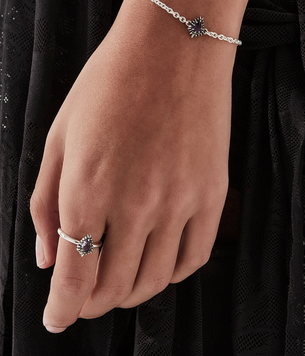 On-model female hand view of the ring styled with other silver jewellery, shown for scale.