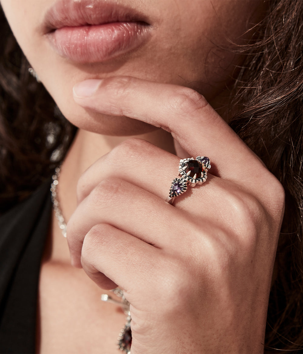 On-model view of silver triple gemstone ring on female hand, dark background
