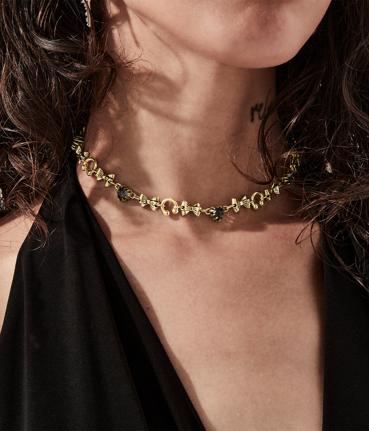 Gold bow charm necklace styled on female model for scale and proportion