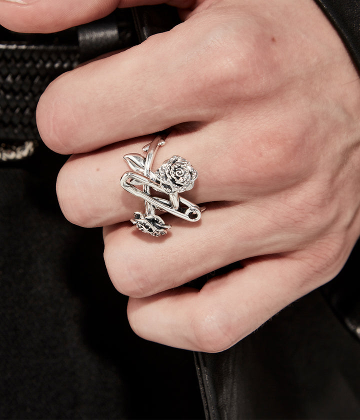 Close up of  sterling silver rose and pin ring with white topaz on hand of model showing intricate detailing.