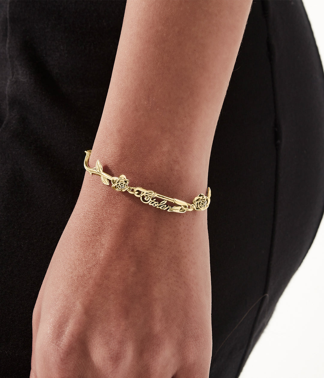 Sculptural gold rose bracelet styled on wrist to show scale and fit.