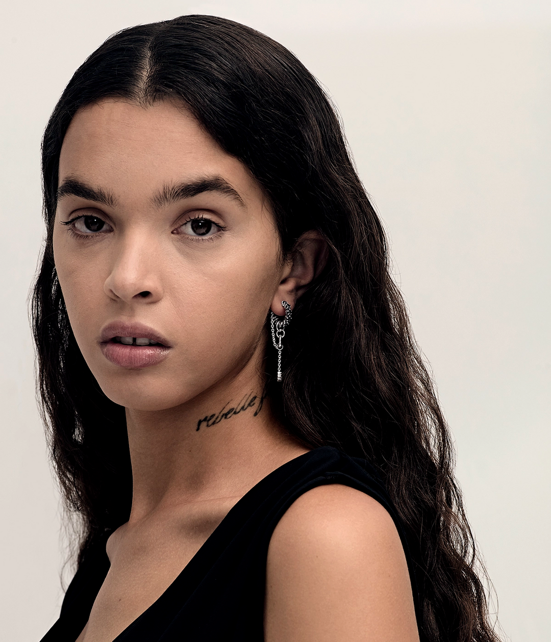 Model wearing elongated Metasoma Eternity Hoops in sterling silver with faceted Clear Quartz and cascading chains that move below the ear.