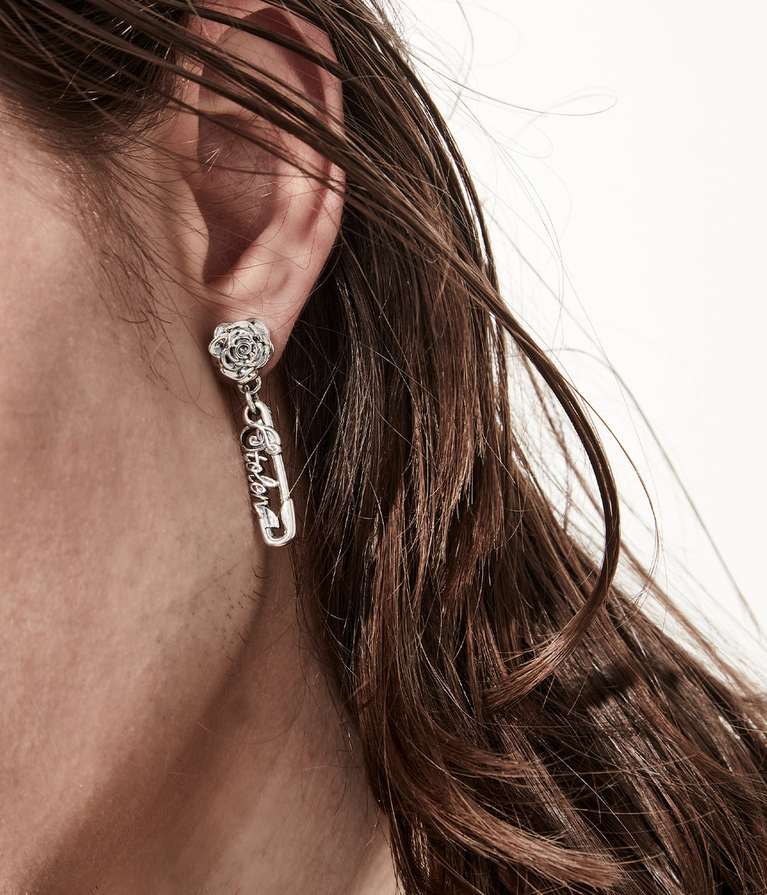 Sterling silver rose pin earrings worn close up to show detailing and scale on male model, white background.