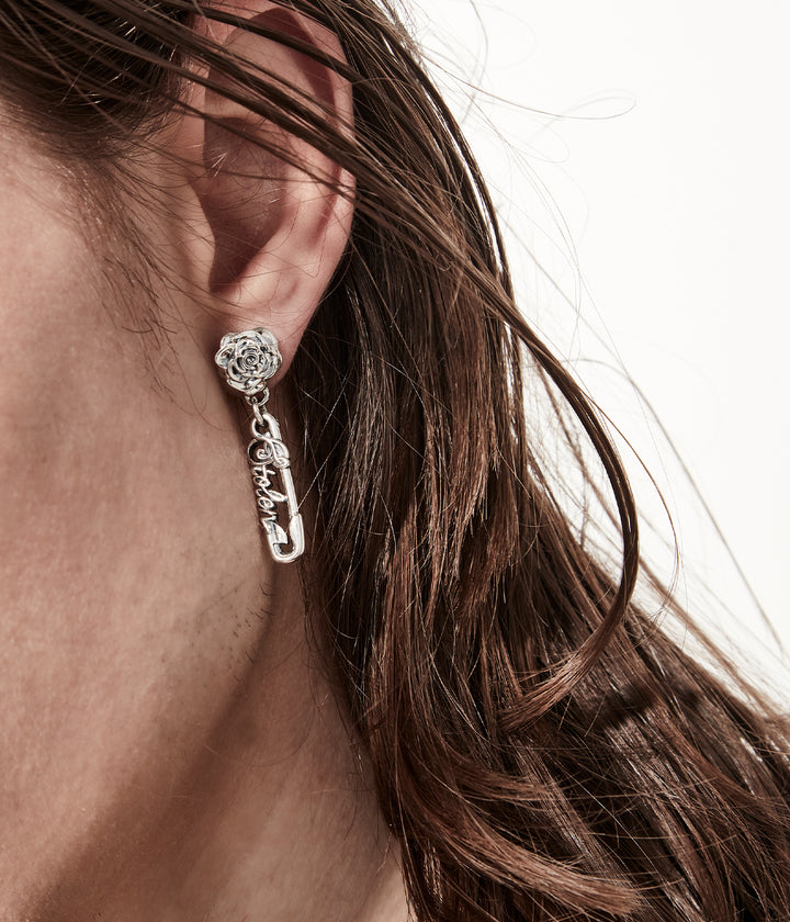 Sterling silver rose pin earrings worn close up to show detailing and scale on male model, white background.