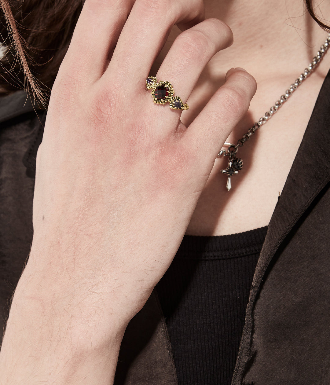 On-model view of gold triple gemstone ring on male hand, dark background