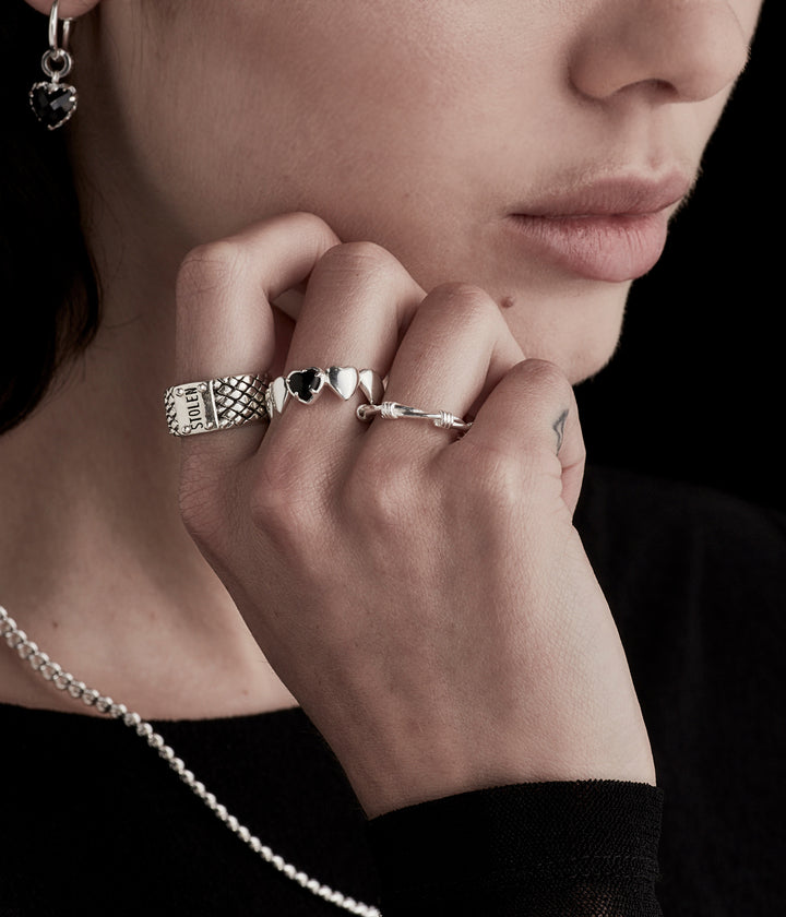 Female model wearing the Band of Hearts Ring in sterling silver, subtly styled to highlight size and wearability.