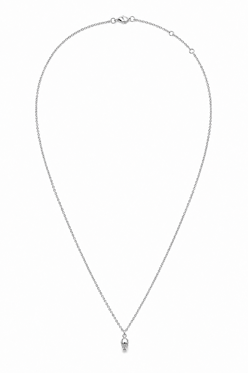 A delicate silver chain necklace with a small skull pendant, displayed on a clean white background.
