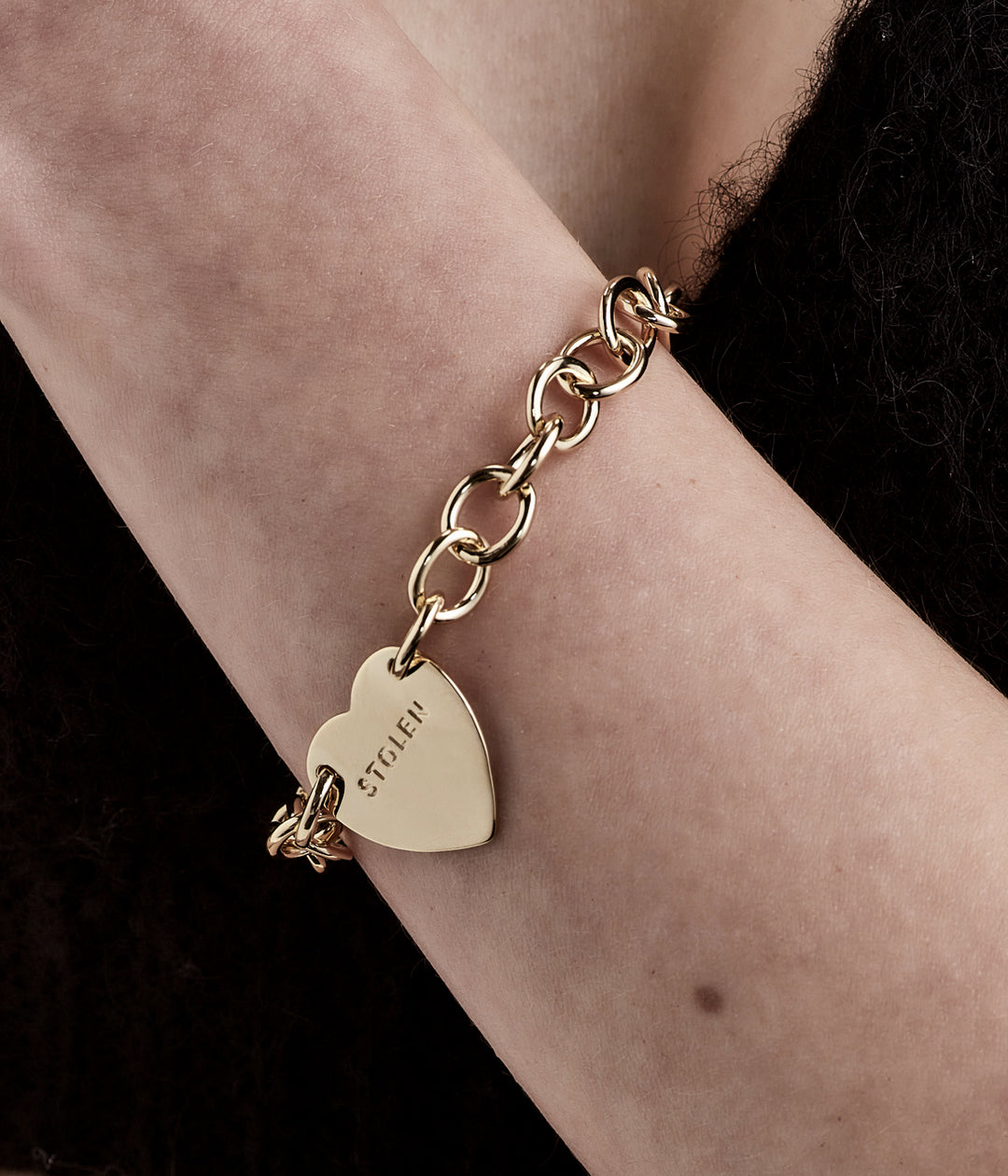Gold chain bracelet worn on female model’s wrist, styled simply to highlight charm and sizing.