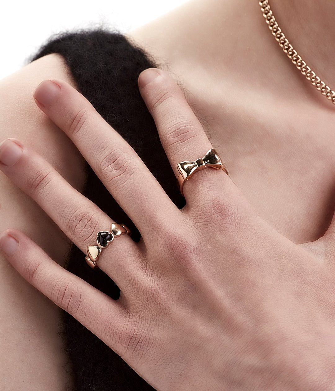 Close-up of female hand wearing Bow Ring in gold, minimal styling to highlight effortless wear.
