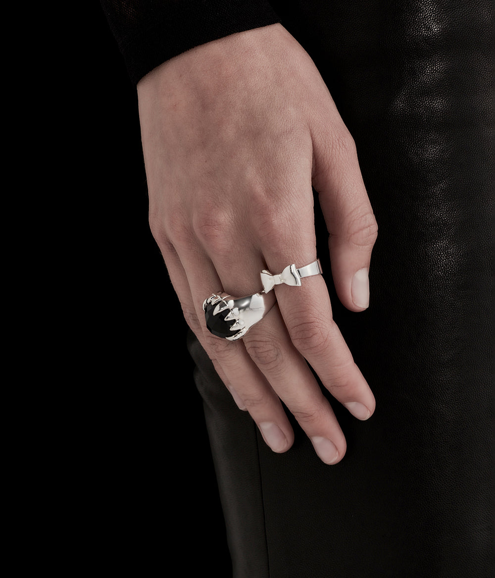 Bow Ring in sterling silver worn by female model in soft contrast lighting, styled with Claw Ring to show signature scale.