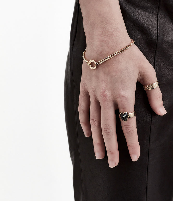 Gold bracelet styled on female model’s wrist, showing fine curb chain and polished finish.