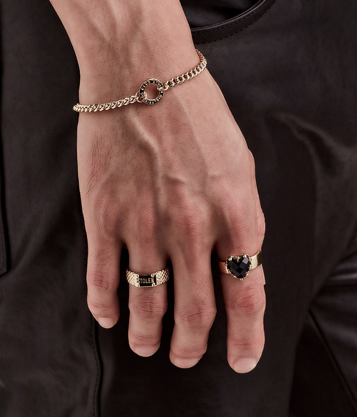 Close-up of gold bracelet worn alone on wrist, styled with two gold plated rings in soft lighting for tone and scale.