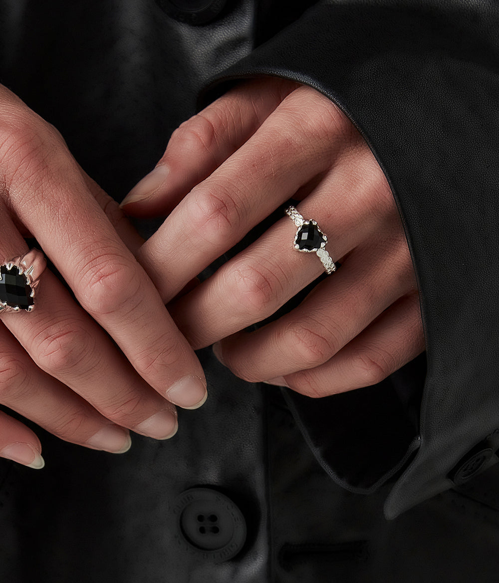 Mini Love Claw Ring on female model’s hand, styled with another onyx ring highlighting heart-shaped black stone and delicate chain-textured band