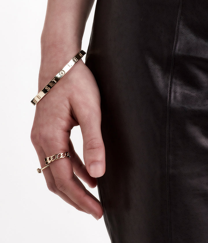 Gold bangle worn on wrist, styled with neutral tones to highlight warmth and proportion.